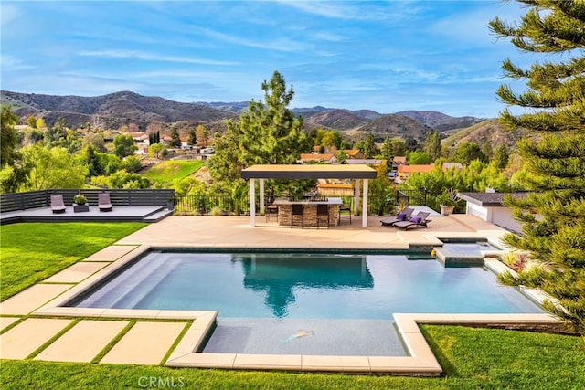 view of pool featuring outdoor dry bar, a patio area, a mountain view, and fence