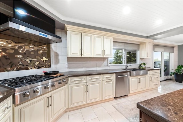 kitchen with cream cabinetry, a sink, appliances with stainless steel finishes, exhaust hood, and crown molding