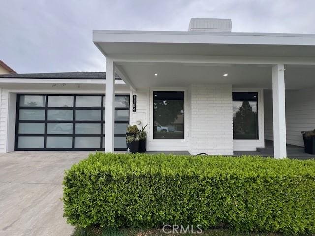 property entrance with brick siding, driveway, and a garage