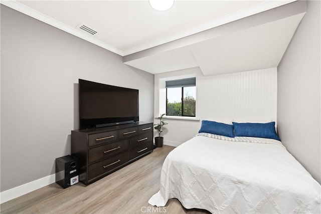 bedroom with visible vents, baseboards, crown molding, and light wood-style floors