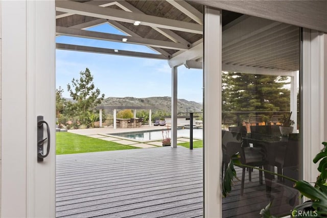 deck featuring a gazebo, an outdoor pool, a mountain view, and a yard