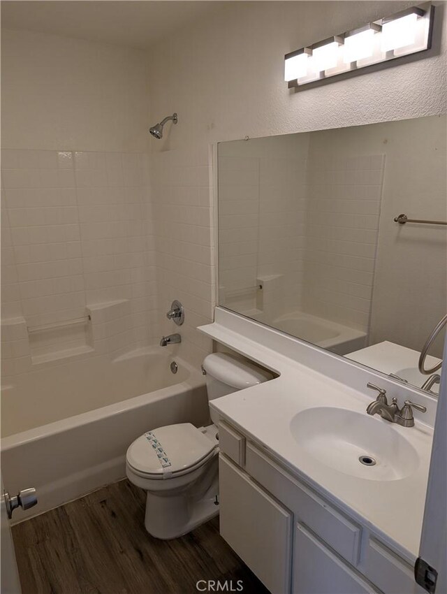 full bath featuring washtub / shower combination, toilet, vanity, and wood finished floors