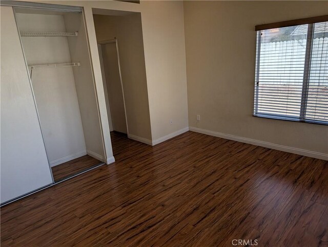 unfurnished bedroom featuring multiple windows, wood finished floors, and a closet