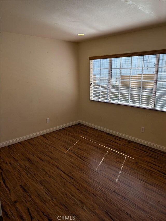 empty room with baseboards and dark wood finished floors