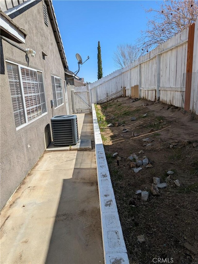 view of yard with central air condition unit, a patio, a fenced backyard, and a gate