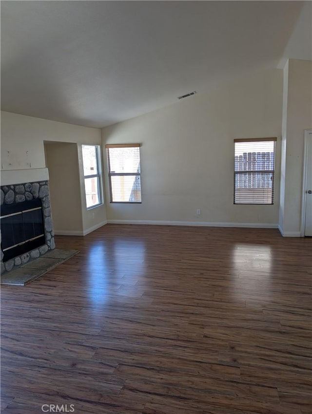 unfurnished living room with visible vents, lofted ceiling, dark wood finished floors, and a fireplace