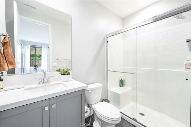 full bath with visible vents, toilet, a stall shower, and vanity