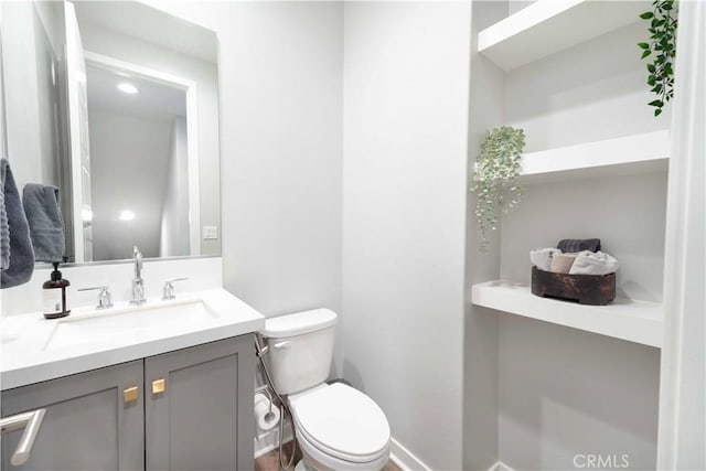 bathroom with vanity, toilet, and baseboards