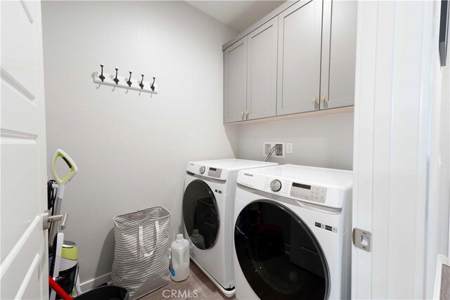 clothes washing area featuring washing machine and dryer and cabinet space