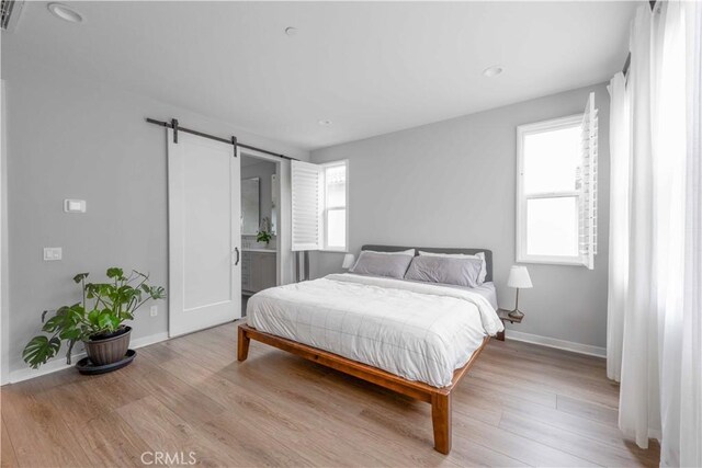 bedroom featuring a barn door, wood finished floors, and baseboards