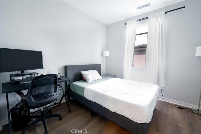 bedroom with visible vents, baseboards, and wood finished floors