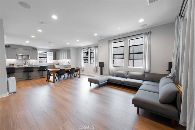 living area featuring light wood finished floors, recessed lighting, and baseboards