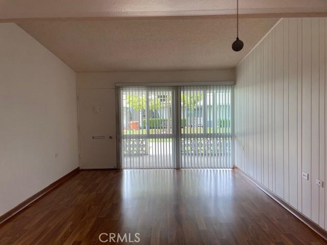 spare room featuring a textured ceiling, baseboards, lofted ceiling, and wood finished floors