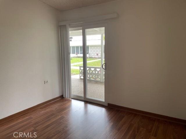 spare room with baseboards and dark wood-style floors