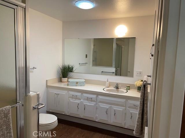 full bathroom featuring an enclosed shower, toilet, wood finished floors, and vanity