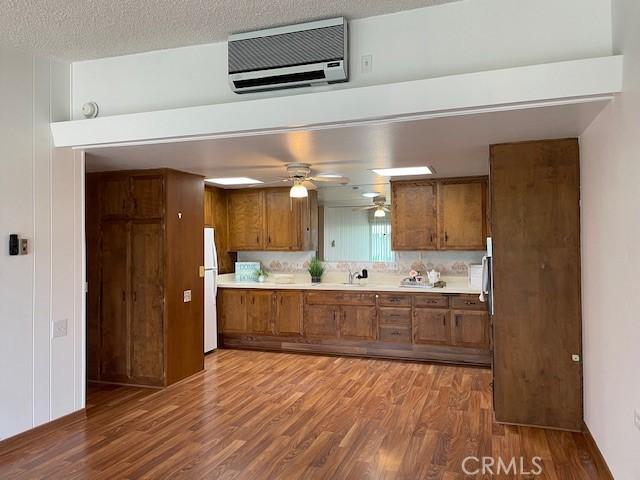 kitchen featuring wood finished floors, brown cabinetry, freestanding refrigerator, and light countertops