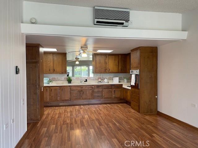 kitchen with baseboards, ceiling fan, dark wood finished floors, light countertops, and brown cabinets