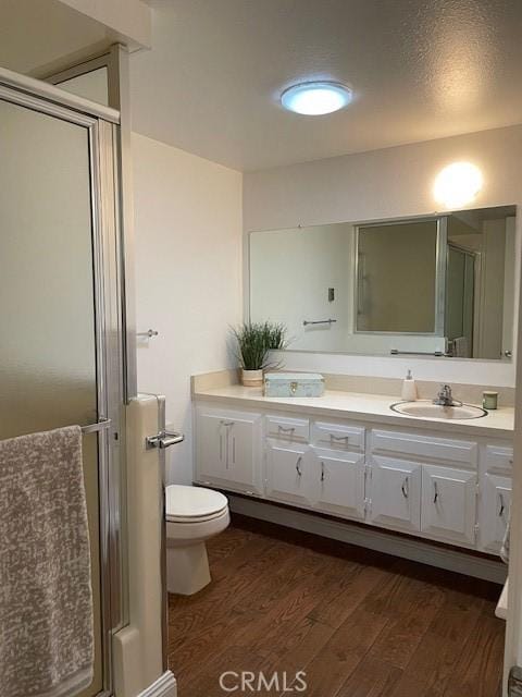 full bath featuring vanity, wood finished floors, a stall shower, a textured ceiling, and toilet