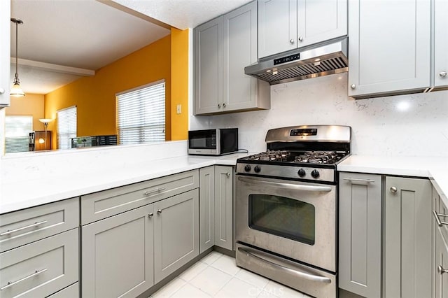 kitchen with under cabinet range hood, decorative light fixtures, light countertops, gray cabinets, and stainless steel appliances