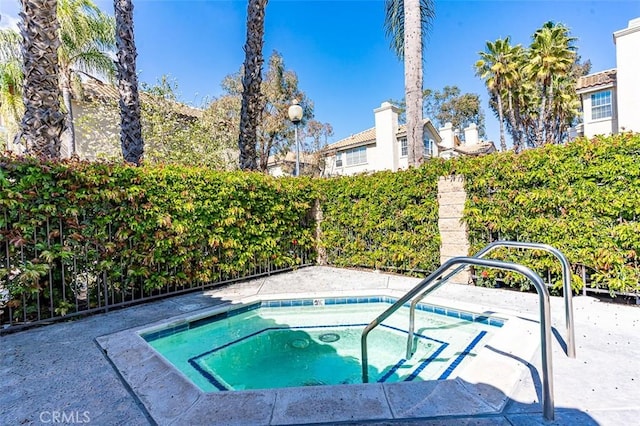 view of swimming pool with fence and a hot tub