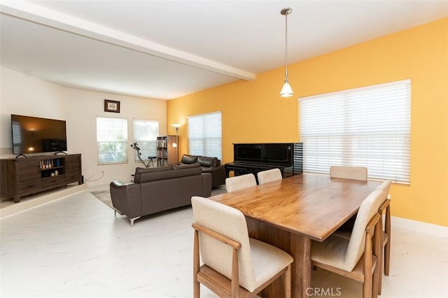 dining space featuring beamed ceiling and baseboards