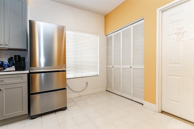 kitchen featuring baseboards, light countertops, gray cabinets, and freestanding refrigerator