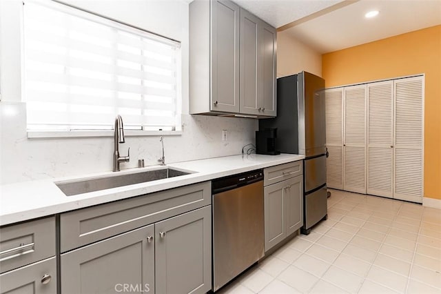 kitchen featuring a sink, stainless steel appliances, backsplash, and gray cabinets