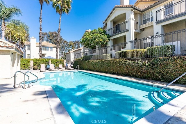 pool with a residential view and a patio