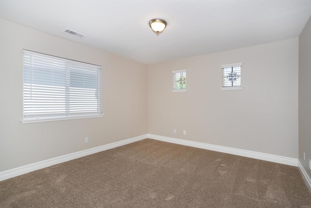 carpeted spare room featuring visible vents and baseboards