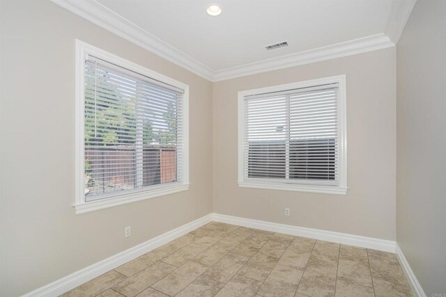 spare room with crown molding, baseboards, and visible vents