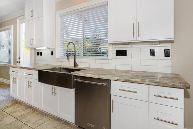 kitchen with a sink, light stone counters, backsplash, white cabinetry, and light tile patterned flooring