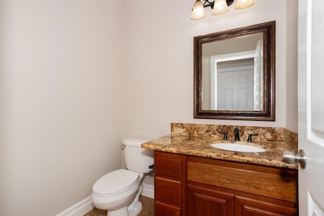 half bathroom with vanity, toilet, and baseboards