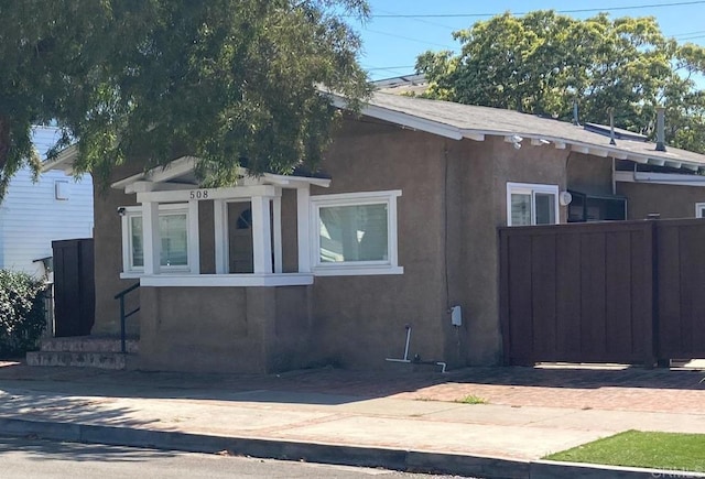 view of side of property with fence and stucco siding