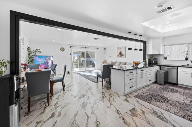 kitchen featuring dark countertops, stainless steel dishwasher, a peninsula, and open floor plan