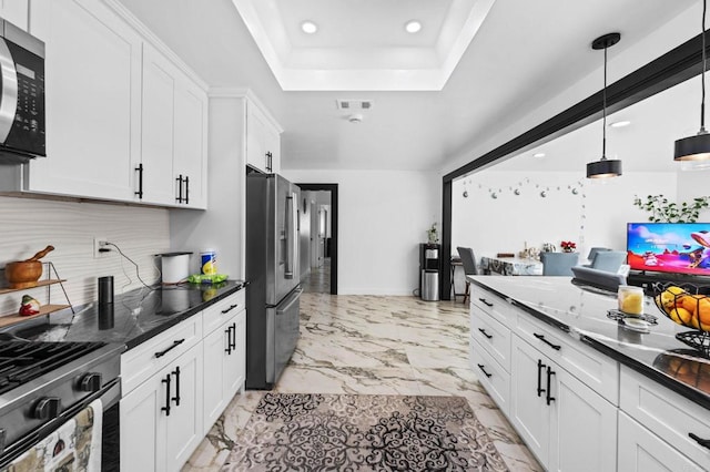 kitchen with marble finish floor, white cabinetry, stainless steel appliances, decorative backsplash, and a raised ceiling