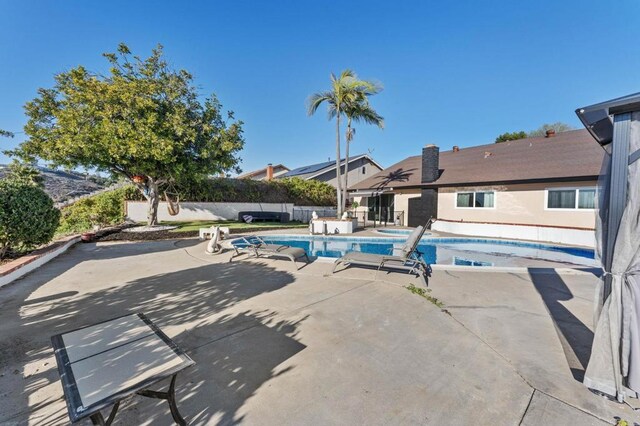 view of swimming pool featuring a jacuzzi, a patio area, a fenced in pool, and a fenced backyard