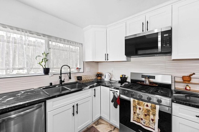 kitchen with a sink, stainless steel appliances, white cabinetry, marble finish floor, and backsplash