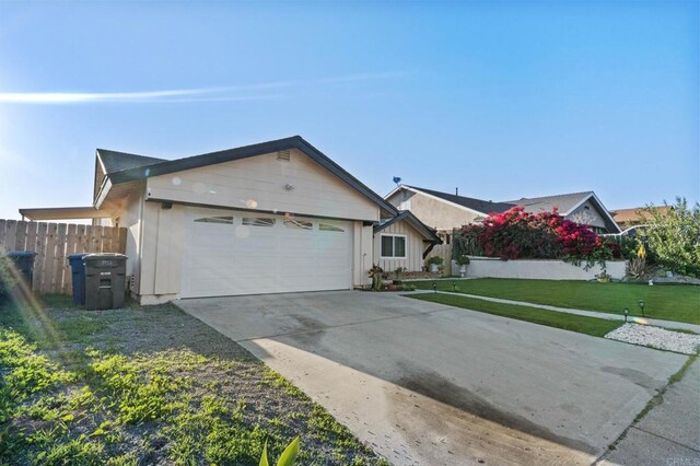 exterior space featuring a front lawn, fence, a garage, and driveway