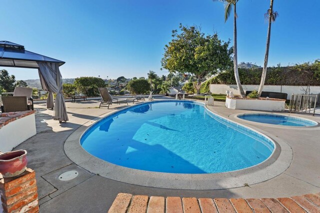 view of swimming pool featuring a patio, a fenced in pool, and an in ground hot tub