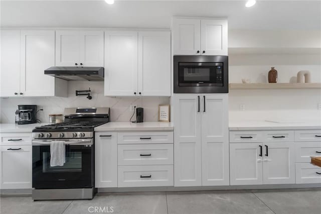 kitchen with under cabinet range hood, decorative backsplash, appliances with stainless steel finishes, white cabinetry, and open shelves