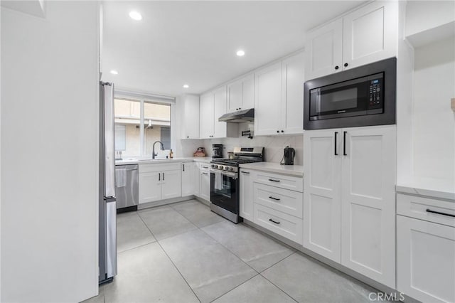 kitchen featuring under cabinet range hood, white cabinets, light countertops, and appliances with stainless steel finishes