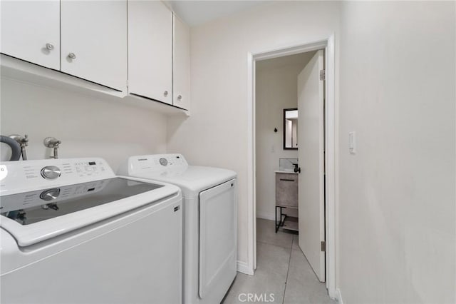 laundry room with cabinet space, washing machine and dryer, baseboards, and light tile patterned flooring