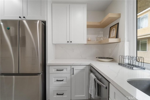 kitchen with open shelves, white cabinets, light stone counters, and stainless steel appliances