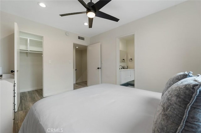 bedroom with visible vents, recessed lighting, ensuite bathroom, wood finished floors, and a sink