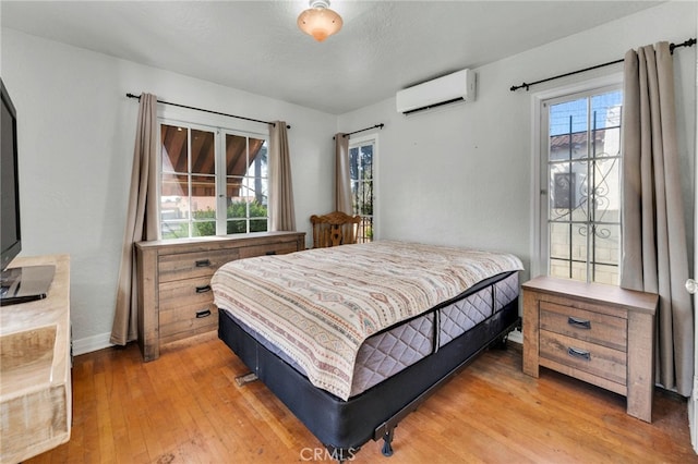 bedroom with light wood-style flooring and a wall mounted AC