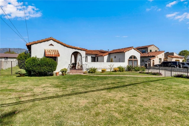 mediterranean / spanish-style home with stucco siding, a front yard, and fence