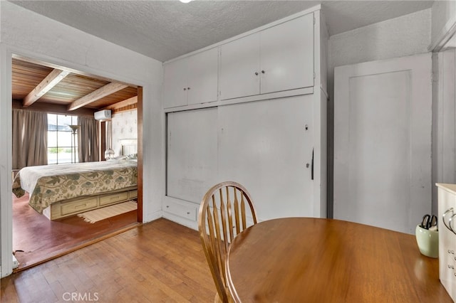 interior space featuring wood finished floors, a wall mounted AC, beam ceiling, wood ceiling, and a closet