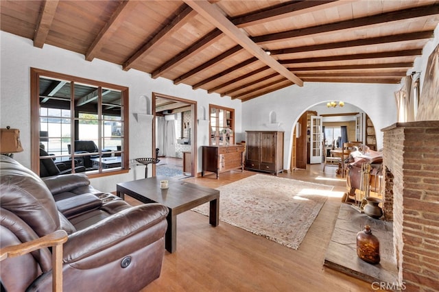 living room with arched walkways, wooden ceiling, vaulted ceiling with beams, and wood finished floors