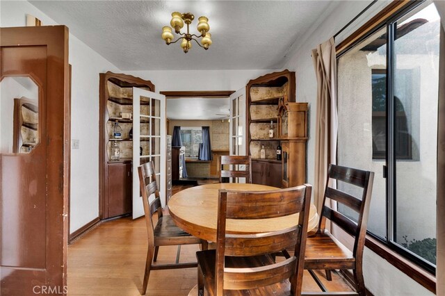 dining area with plenty of natural light, a textured ceiling, baseboards, and wood finished floors