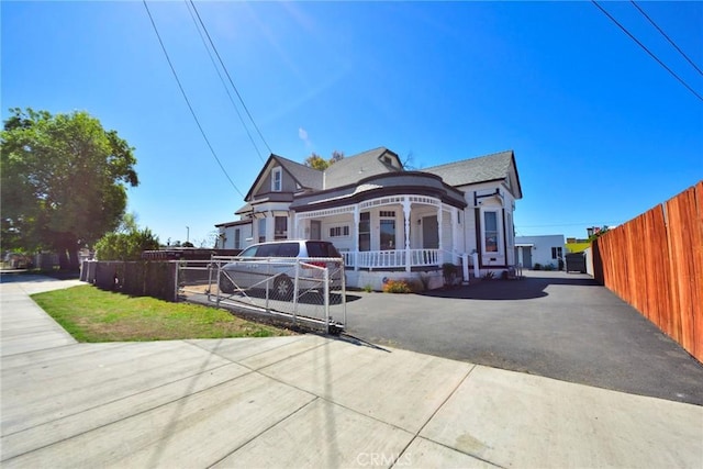 view of front of house featuring a porch, fence, and aphalt driveway